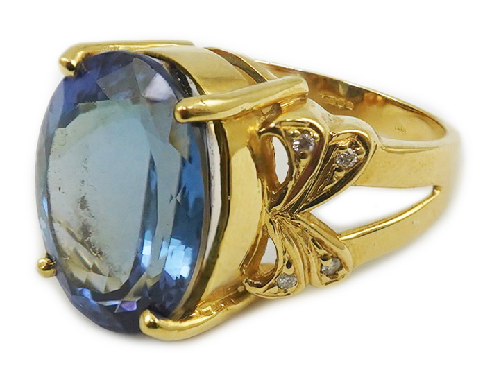 A modern 18ct gold and single stone oval cut tanzanite set dress ring, with eight stone diamond chip set shoulders